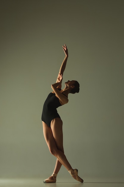 Anmutiger Balletttänzer oder klassischer Ballerinatanz einzeln auf grauem Studiohintergrund. Flexibilität und Anmut zeigen. Das Konzept Tanz, Künstler, Zeitgenössisch, Bewegung, Aktion und Bewegung.