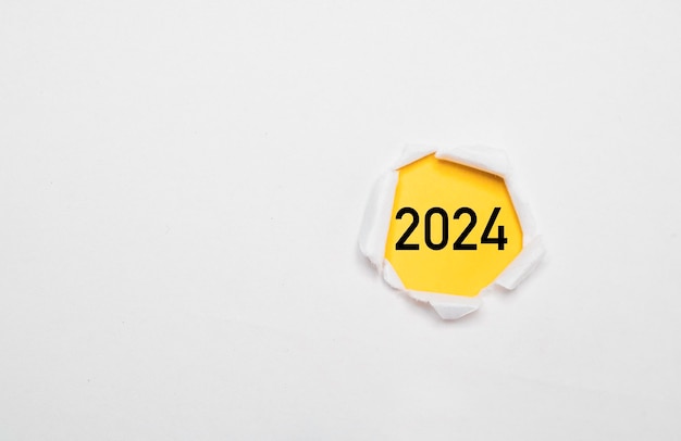 Año 2024 en papel amarillo y dentro de papel perforado blanco para la preparación de Feliz Navidad y Feliz año nuevo para comenzar el cambio de negocio y el concepto de planificación