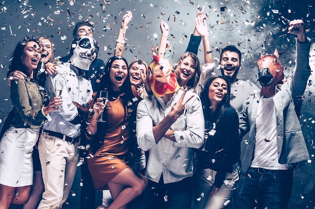 Ano do galo. grupo de jovens com máscaras de animais jogando confete e parecendo felizes