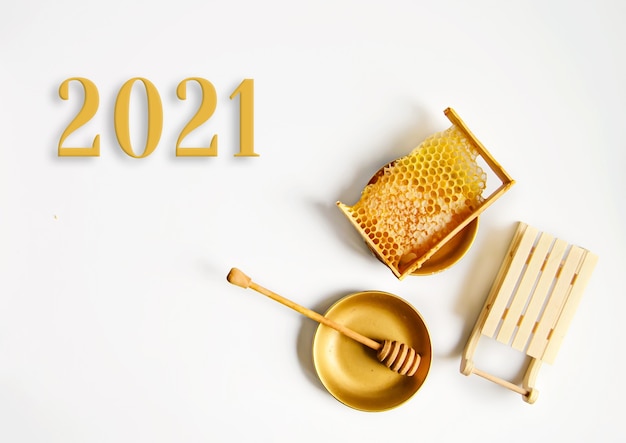 Ano novo 2021, favo de mel amarelo quebrado com mel na mesa ao lado de trenós decorativos