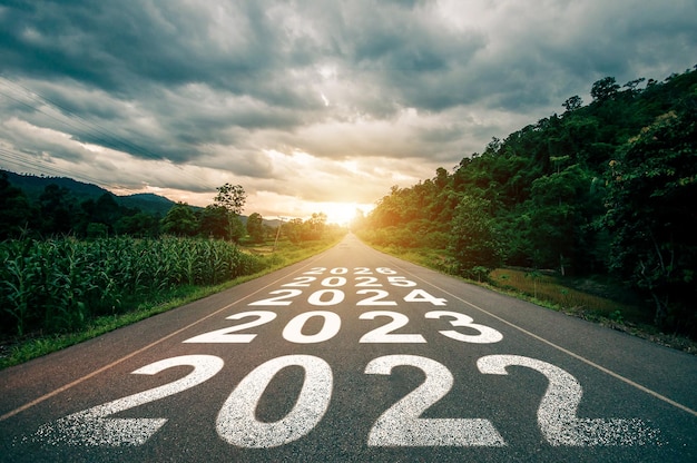 Ano novo 2023 2024 2025 2026 ou conceito direto Texto 2023 escrito na estrada no meio da estrada de asfalto com o pôr do sol Conceito de planejamento meta desafio resolução de ano novoxA