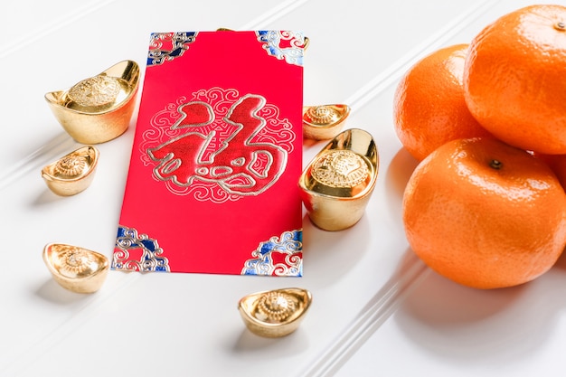 Ano novo chinês vermelho ang pow com lingotes de ouro e tangerina na mesa, língua chinesa significa