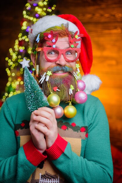 Ano novo com chapéu de Papai Noel com bolas decorativas na barba e feliz Natal feliz.