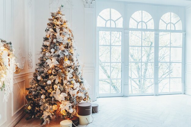 Ano novo de Natal clássico decorado quarto interior Árvore de ano novo. Árvore de Natal com enfeites de ouro. Apartamento de design de interiores de estilo clássico branco moderno, janela grande. Véspera de Natal em casa.