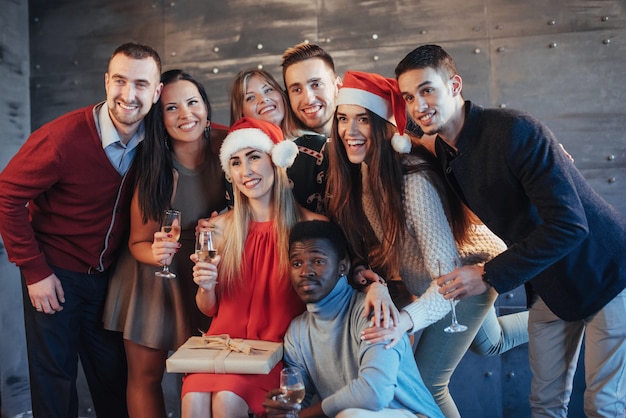 Ano novo está chegando! Grupo de jovens alegres multiétnicas em chapéus de Papai Noel na festa, posando conceito de estilo de vida emocional das pessoas