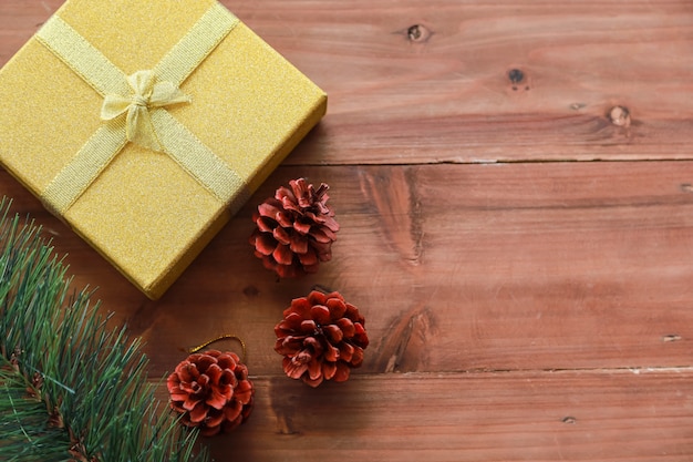 Ano novo, Natal e conceito de tempero de férias. Feche acima da caixa de presente do ouro com fita bonita e pinhas dos ornamento e árvore do xmas na prancha de madeira com espaço da cópia.