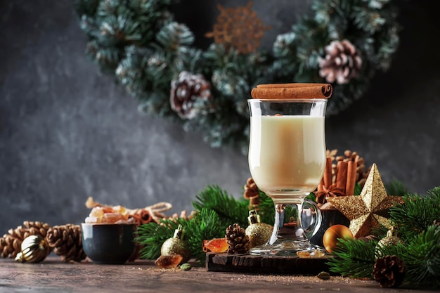 Ano novo ou Natal Eggnog cocktail inverno quente ou bebida de outono com ovos de leite e rum escuro polvilhado com canela e noz-moscada em um copo na decoração festiva de fundo de madeira