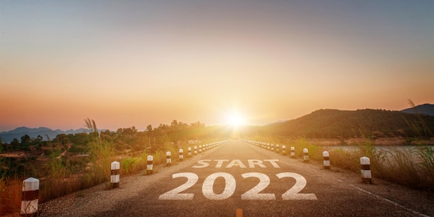 Año nuevo 2022 escrito en la carretera. carretera de asfalto vacía y fondo de cielo hermoso amanecer. concepto de meta y desafío para la visión 2022.