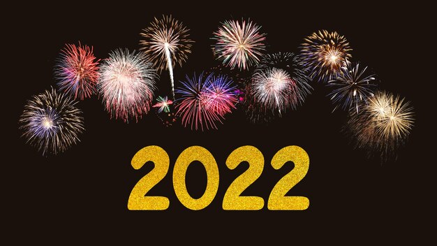 Año nuevo 2022 sobre un fondo negro grandes coloridos fuegos artificiales detrás de él.