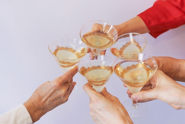 Foto año nuevo celebrando las manos con copas de vino espumoso blanco