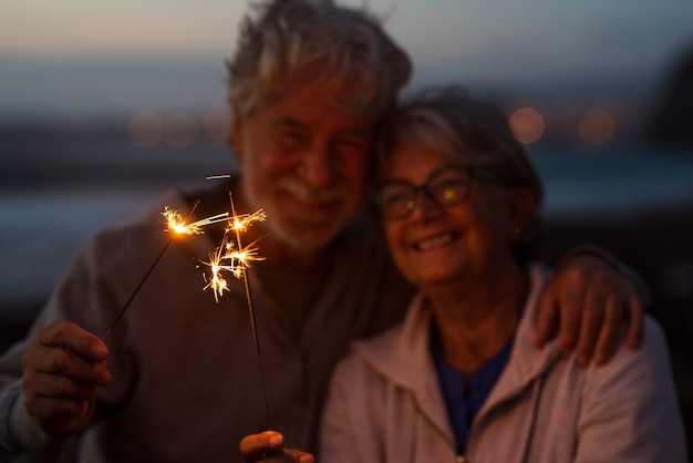 Año nuevo. Cerca de las personas mayores celebrando el año nuevo juntos en la playa con luces de bengala