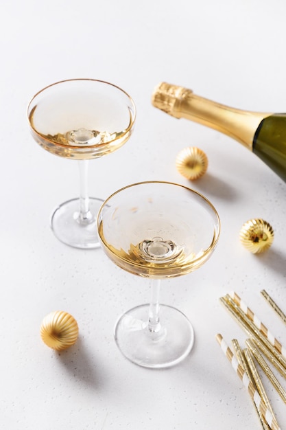 Año nuevo champagne y adornos navideños de oro sobre fondo blanco.