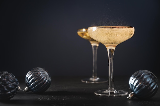 Año nuevo champagne en copas de vino y botella en balde decorado con adornos de navidad azul