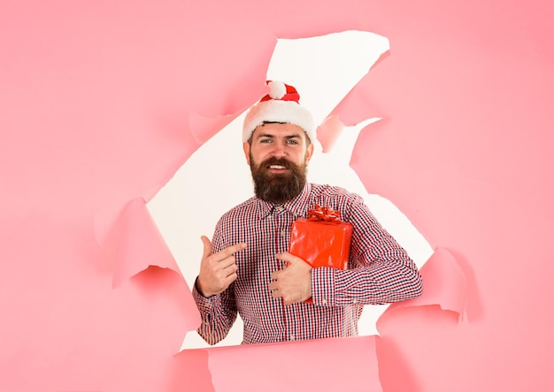 Año nuevo invierno regalos de navidad hombre de santa muestra con el dedo en la caja de regalo hombre barbudo con sombrero de santa