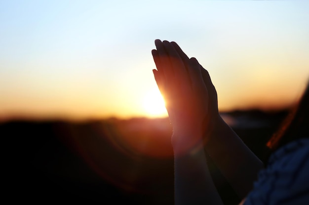 Año nuevo luz del amanecer brillando entre el sol naciente y orando manos cristianas deseo concepto