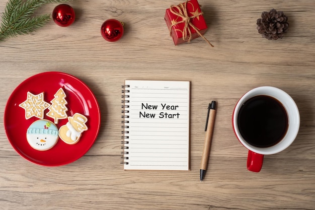 Año Nuevo Nuevo Comienzo con taza de café negro portátil Galletas de Navidad y bolígrafo sobre mesa de madera Resolución de objetivos de Navidad Lista de tareas Concepto de estrategia y plan