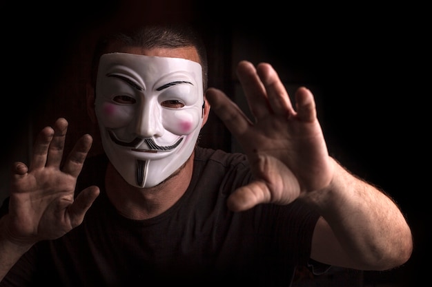 Anônimo com máscara de Guy Fawkes com as mãos levantadas.