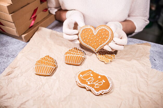 Anonyme Frau, die einige hausgemachte Herz-Lebkuchen-Kekse an der Küche verziert