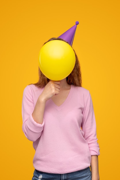 Anonyme Frau, die Gesicht mit Geburtstagsballon bedeckt