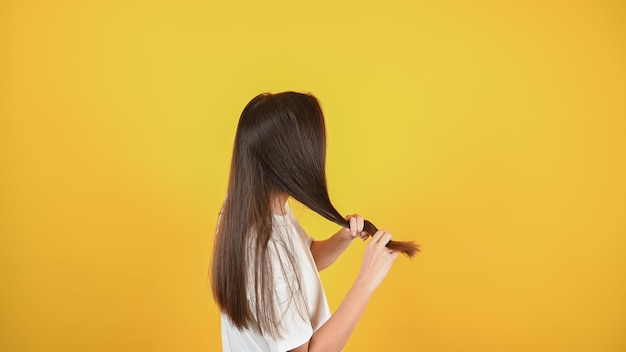 Anonyme Frauenhand, die ihr langes Haar mit Blick auf beschädigte Splissenden von Haarpflegeproblemen hält