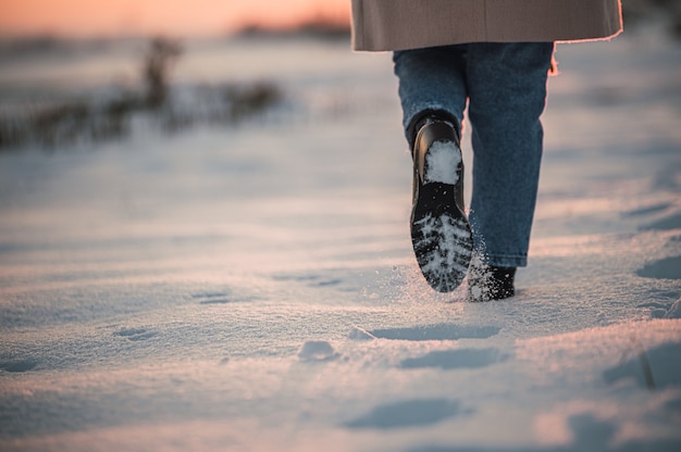 Anonyme Person, die auf schneebedecktem Feld geht