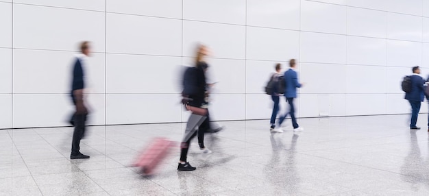 Anonyme unscharfe Menge von Geschäftsleuten geht auf einer Messe oder auf einem Flughafen mit Ausrüstung spazieren