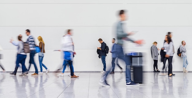 Foto anonyme unscharfe menge von geschäftsleuten geht auf einer messe oder auf einem flughafen mit ausrüstung spazieren