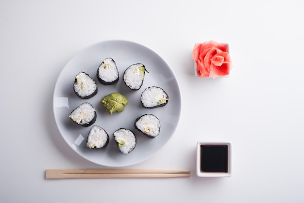 Anrichten von vegetarischen Sushi-Rollen aus Avocado und Gurke mit Ingwer-Wasabi und Sojasauce
