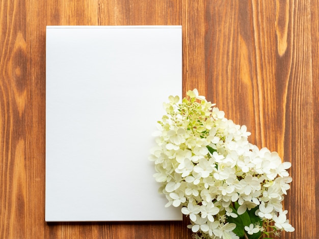 Anschlagtafel mit leerem blatt für anmerkungen und abstrakter leerer hölzerner hintergrund der hortensie der weißen blume.