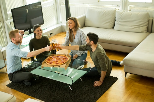 Ansicht an der Gruppe Freunde Pizza essend und Apfelwein zusammen zu Hause trinkend