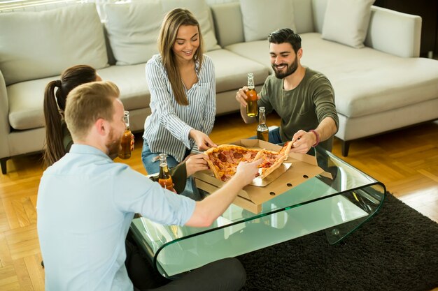 Ansicht an der Gruppe Freunde Pizza essend und Apfelwein zusammen zu Hause trinkend