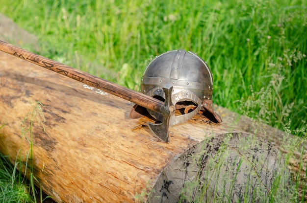 Ansicht der alten Wikinger-Rüstung, die auf einem Holzscheit liegt Helm und Axt Historisches Fotokonzept