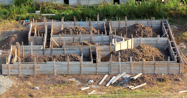 Ansicht der Baustelle und der Holzhausgrundlage im Vorbereitungsprozess. Kellerbau. Betonfundament für ein neues Gebäude
