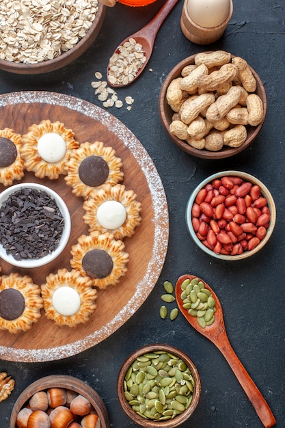 Ansicht der oberen Hälfte Kekse mit Schokolade und dunkler Schokolade auf Holzbrettschalen mit Nüssen Holzlöffel auf dem Tisch