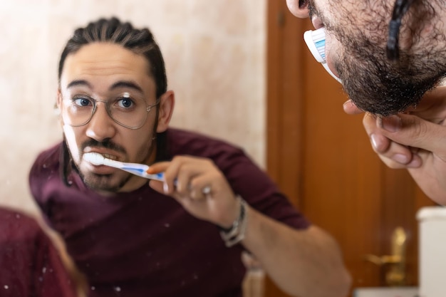Ansicht des Mannes beim Zähneputzen im Badezimmerspiegel Reflexion des Mannes beim Zähneputzen im Badezimmer