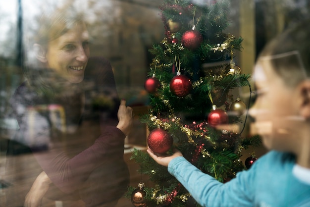 Ansicht einer Mutter und eines Kindes an Weihnachten, die einen Weihnachtsbaum schmücken