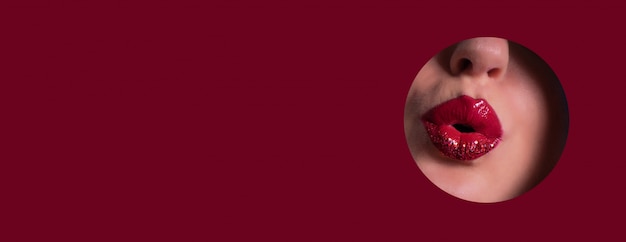Ansicht von den schönen roten Lippen, die Kuss durch Loch im Papierhintergrund geben
