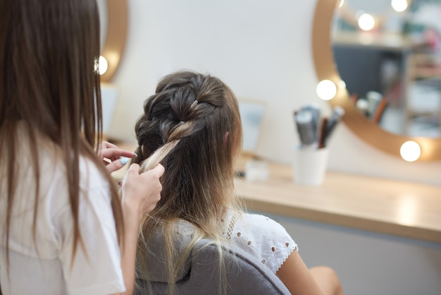 Ansicht von der Rückseite des Friseurs zwei Ährchen zum Kunden im Schönheitssalon flechtend