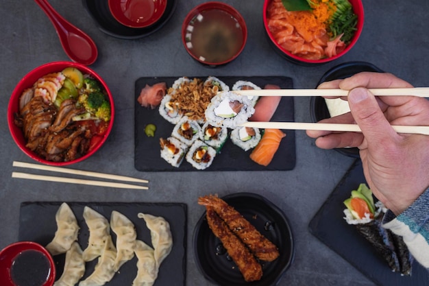 Ansicht von man39s Händen, die Sushi im japanischen Restaurant essen Hochwinkelansicht von Sushi-Händen mit Stäbchen auf dem Tisch