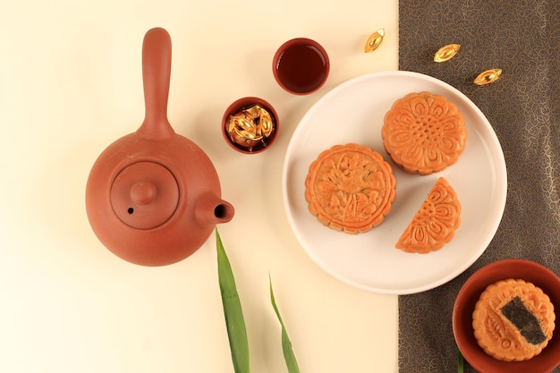 Ansicht von oben abstraktes Stillleben Mitte Herbst Festival Snack Moon Cake auf cremefarbenem Hintergrund mit jungem Bambusbaum, ausgewählter Fokus, Textfreiraum