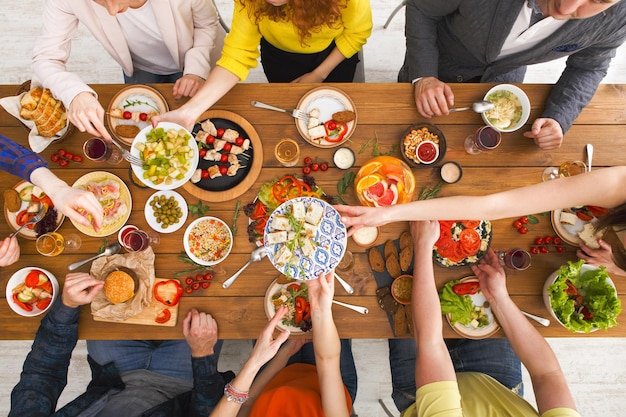 Ansicht von oben auf den Tisch der Freunde. Leute essen zusammen gesundes Essen, Hausparty