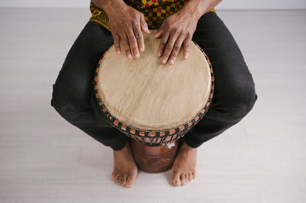 Ansicht von oben des afroamerikanischen männlichen Musikers, der zu Hause traditionelles Schlagzeug spielt. Online-Musikunterrichtskonzept. Freizeit und Musikinstrumente lernen. Rhythmus in ethnischen multikulturellen Traditionen.