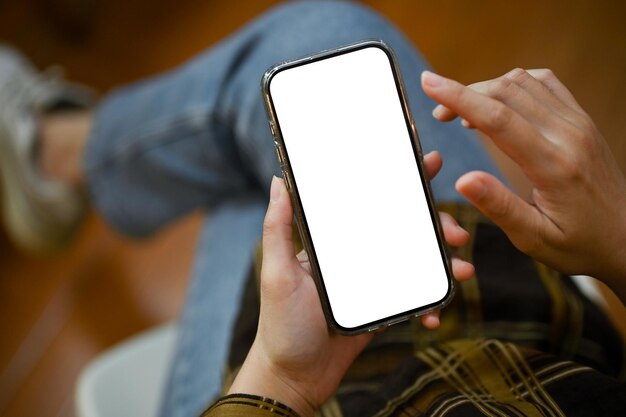 Ansicht von oben Eine Frau, die ihr Smartphone benutzt, während sie entspannt in ihrem Zimmer sitzt