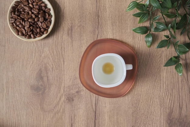 Ansicht von oben flach legen Kaffee weiße Tasse auf hölzernen Desktop Espresso Heißgetränk Gesundheit Grüne Pflanze auf dem Tisch in einem Café oder zu Hause Kaffee mit Getränk zum Beenden und leere Tasse