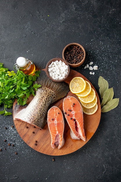 Ansicht von oben frischer Fisch mit Zitronenscheiben und Gewürzen auf dem dunklen Hintergrund Meeresfrüchte Mahlzeit Essen Mahlzeit Wasser Fisch Fleisch Ozean Salat Meer