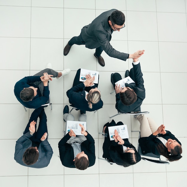 Ansicht von oben. glückliche mitarbeiter geben sich gegenseitig ein high five bei einem arbeitsmeeting.