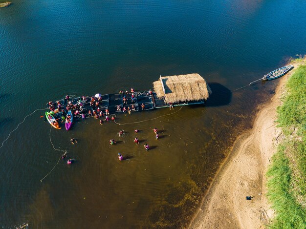 Ansicht von oben Menschen spielen Wasser in der Nähe eines Holzfloßes, das auf dem Fluss Chanaburi Thailand schwimmt