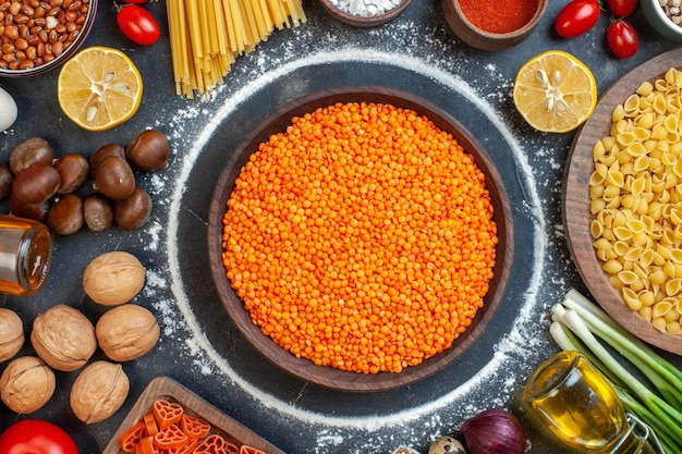 Ansicht von oben orangefarbene Linsen mit Eiern, Nüssen, Gemüse, rohe Nudeln und Gewürze auf dem dunklen Hintergrund, Rohkost, Küche, Farbfoto, Kuchen