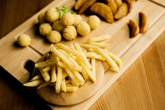 Ansicht von oben Sortiment KartoffelnGebackene Bratkartoffeln auf einem Holzteller serviert mit TomatensaucePommes Wedges KartoffelkrokettenKartoffelpüree Bällchen paniert und frittiert Landschaft