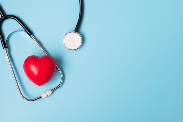 Ansicht von oben Stethoskop mit roter Herzform auf blauem Hintergrund mit Kopienraum für Text. Gesundheitswesen, Lebensversicherung, Gesundheitstag, Weltherztag und Happy Doctor Day Konzept
